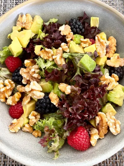 A beautiful salad with mixed greens, avocado, walnuts, and fresh berries. The crunch of the nuts combined with the creaminess of the avocado makes this a truly satisfying meal.