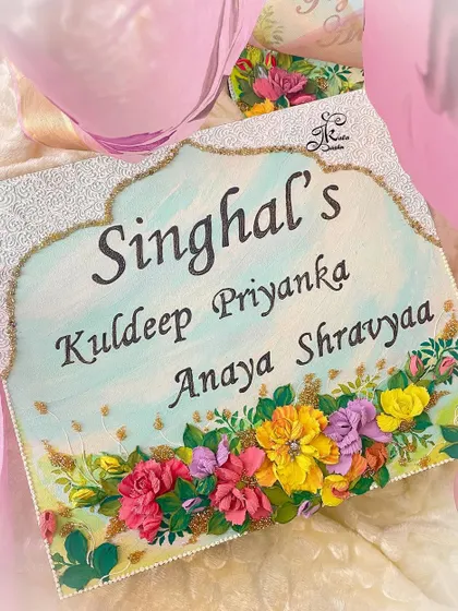 An elegant nameboard for the "Singhal" family, featuring a turquoise base and a beautiful arch design. The bottom is adorned with a garden of colorful flowers.