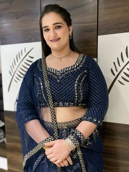 A simple yet elegant look for a party, featuring a subtle smokey eye and a glossy lip. The hair is styled straight and sleek, complementing the modern navy blue lehenga.