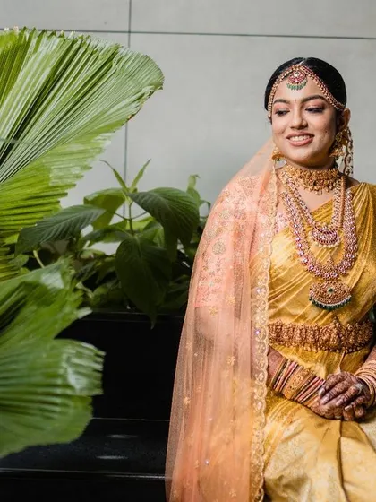 A portrait of a South Indian bride looking serene and beautiful. Her traditional gold jewelry and elegant saree are perfectly complemented by the modern, minimalist background.