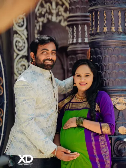 A cheerful couple portrait against a dark, ornate pillar, highlighting their bright smiles.