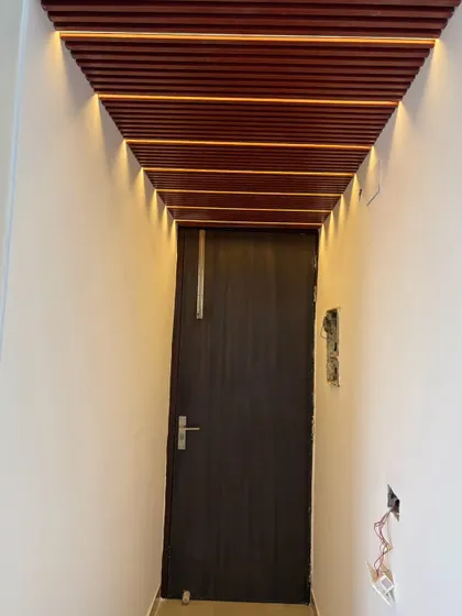 A view of a hallway with a wooden rafter ceiling and integrated lights, leading to the main living area. This is a great way to make a passage more interesting.