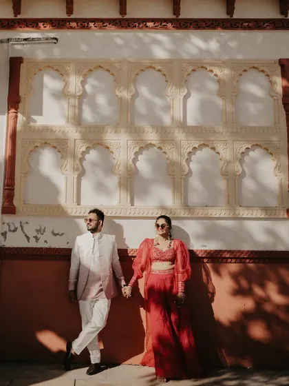 Using shadows and light to create a dramatic effect. The couple stands against a traditional Indian wall, the afternoon sun casting beautiful shadows that add depth and artistry to the portrait.