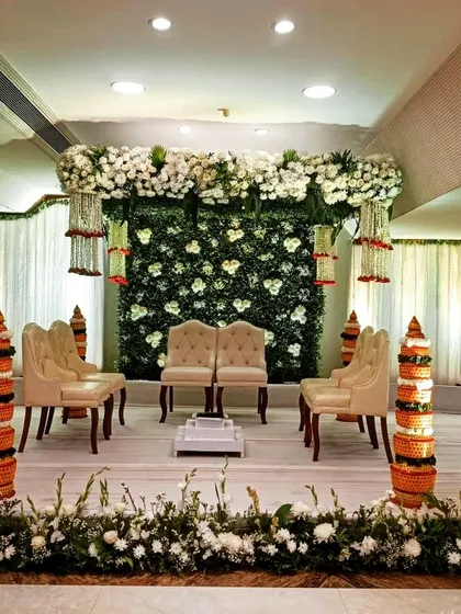 This setup for a Vidhi-cum-Reception event features a clean white and green floral theme. The stage includes traditional Matki pillars, blending sacred ceremony elements with a modern reception look.