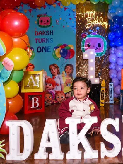 The birthday boy sitting proudly amidst his party decorations.
