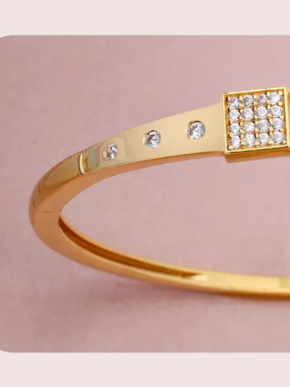 A modern gold kada featuring square panels set with diamonds. The clean lines and minimalist design make it a chic and versatile accessory for any wardrobe.