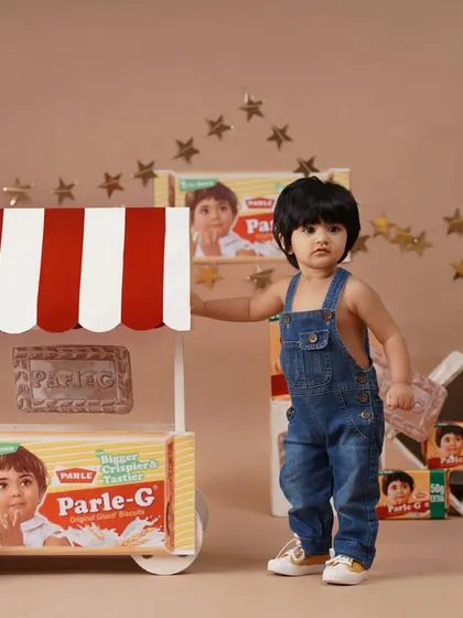 A full-length standing pose of the baby girl next to her Parle-G cart, perfect for a nostalgic and creative birthday memory.
