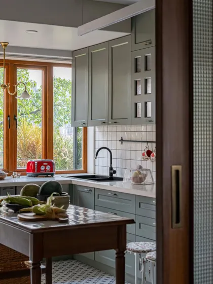 A glimpse into the Calcutta kitchen, where a bright red toaster adds a pop of color. The large window looks out onto the garden, flooding the space with natural light and making it a beautiful place to start the day.