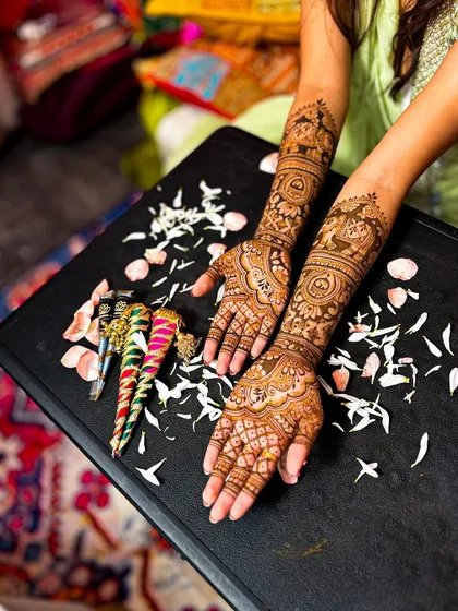 An artistic shot of the bridal mehendi, with fresh henna cones and flower petals, highlighting the tools of my trade.