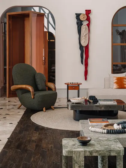A detail shot of the informal living room, showing the rich textures of the armchair and the stone coffee tables. The space is designed to be a comfortable, stylish hub for family life.
