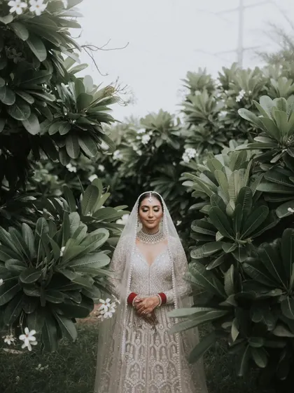 A serene portrait of the beautiful Sikh bride, Jasleen. Her elegant white attire is perfectly complemented by the natural green backdrop of the venue.