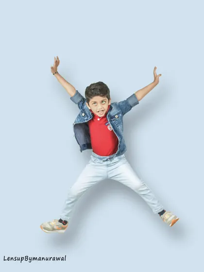 A high-energy, fun shot of a young boy jumping for joy in a studio, capturing his dynamic personality and the boundless spirit of childhood.