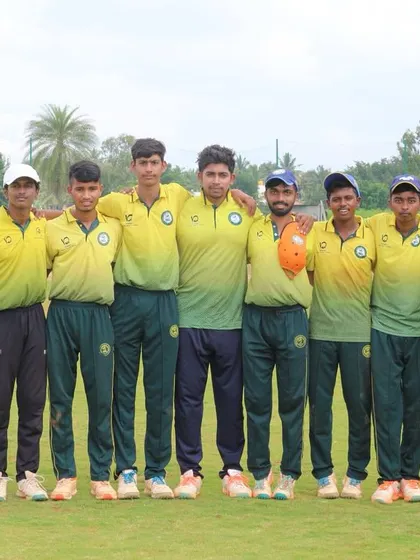 A youth team in yellow jerseys poses for a group photo on the field.