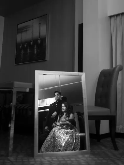 A classic black and white portrait of the couple sharing a quiet moment. The reflection in the mirror adds a layer of artistry to this timeless wedding shot.