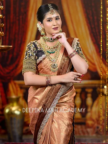 The bride is posed elegantly, showcasing her complete attire. The lighting highlights the sheen of the silk saree and the sparkle of the antique-finish jewelry.