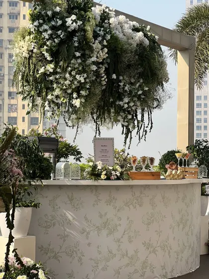 The cocktail bar for the Haldi, with a custom-printed floral front and a dramatic hanging installation of greenery and white flowers above.
