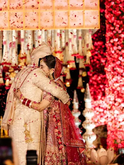 An embrace that says it all. This candid moment of the couple hugging after their varmala, with a shower of petals, is the kind of emotional, heartfelt memory I aim to create.