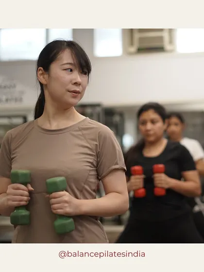 Focus and determination. This client is using light dumbbells to add an upper body challenge to her reformer workout.