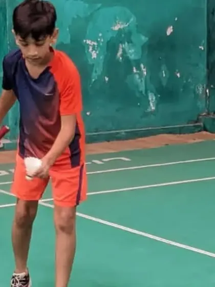 A junior player preparing to serve, demonstrating focus and proper grip.