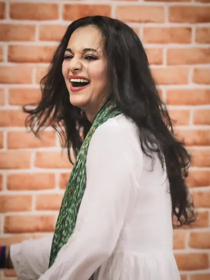 A candid photo filled with laughter against a brick wall. The joy you see here is the same joy I aim to bring to your sangeet practice.