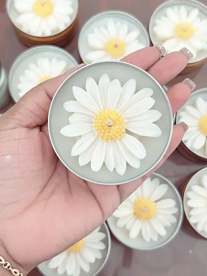A close-up of the daisy tin candle, held in my hand. The detail on the wax flower is something I'm very proud of.