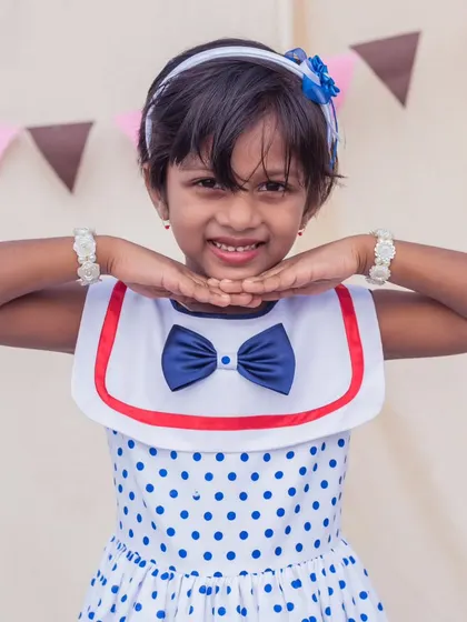 A close-up of the adorable sailor collar and bow on this polka dot dress. It’s a timeless detail that adds a touch of nautical charm.