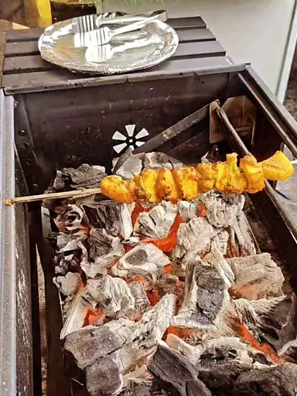 A single skewer of freshly grilled vegetarian tikka rests over the hot coals of our barbecue pit. This shot captures the essence of our live grill service, focusing on fresh, hot, and smoky appetizers.