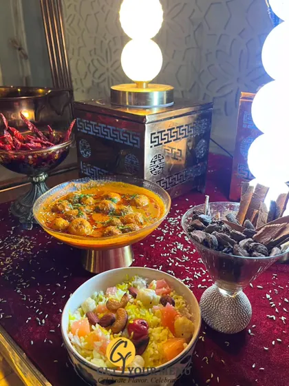 A beautiful display of our main course dishes, including a rich kofta curry and a colorful Navratan Pulao, surrounded by the whole spices that give them their unique aroma.