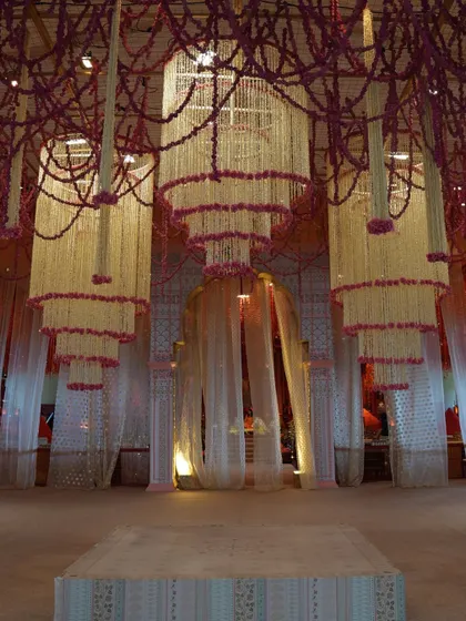 The bride's grand entrance, framed by ethereal floral chandeliers, creating a fairytale moment.