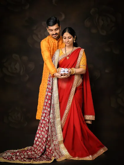 A classic portrait of a couple during their traditional maternity shoot. They are holding a tiny pair of baby shoes, a sweet symbol of the new life they are awaiting.
