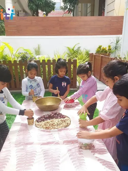 A group of children works together at an outdoor table to prepare the modak ingredients. We take learning outdoors whenever possible to connect with nature.