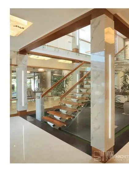 The grand staircase at Mannath House, with its floating wooden steps and marble-clad pillars, creates a stunning focal point in the home's entrance.