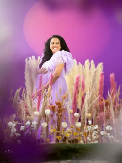 A joyful and vibrant portrait in a field of lavender-hued flowers. The mom-to-be's happy expression and the colorful setting create a feeling of pure bliss.