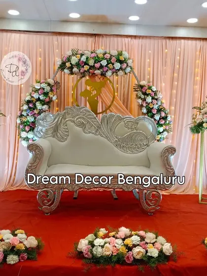 A lovely baby shower package decor. This setup includes a floral ring backdrop, a stylish silver chaise lounge, and matching flower stands for a cohesive and elegant look.