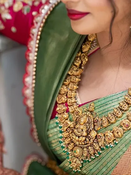 A detail shot showcasing the rich texture of the Kanjeevaram silk and the intricate temple jewelry that completes the traditional South Indian bridal look.