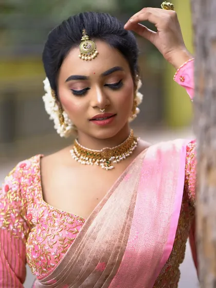 A side profile showing the elegant hair updo adorned with fresh flowers. This angle also highlights the contouring and glow on the cheekbones.