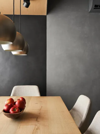 A detail of the dining nook in AD House. The ash wood ceiling and brass pendant lights create a cozy, defined zone within the larger open-plan living area.