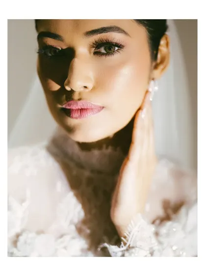 A beautiful close-up bridal portrait. The dramatic lighting highlights the bride's features and the intricate details of her dress, creating a striking and elegant shot.