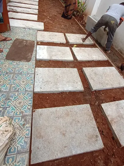 Our team fits large stepping stones along a narrow side yard, with exposed soil around the path before grass laying.