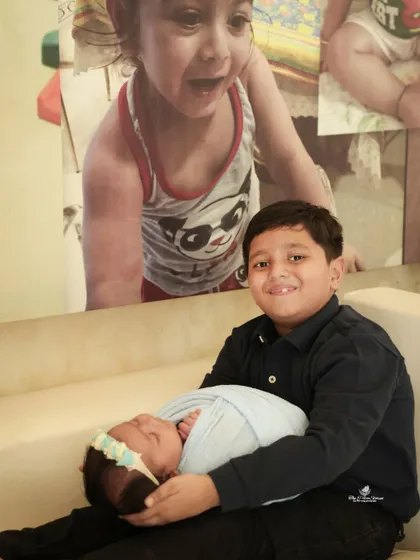 A proud big brother holding his new baby sister. This is a heartwarming shot that captures the beginning of a special sibling bond.
