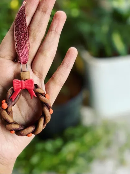 A handmade ceramic wreath ornament, complete with a little red bow. These small, detailed pieces are a joy to make.