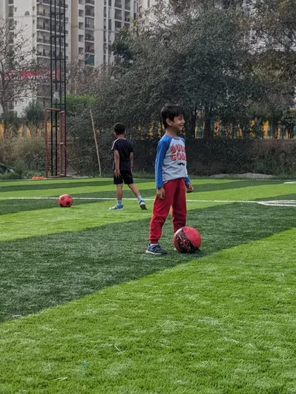 A young player takes a moment during a drill, happy to have a football at his feet on the training ground.