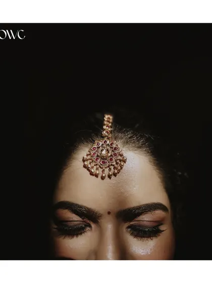 An artistic close-up focusing on the bride's 'Netti Chutti' or maang tikka, a key piece of bridal jewellery.