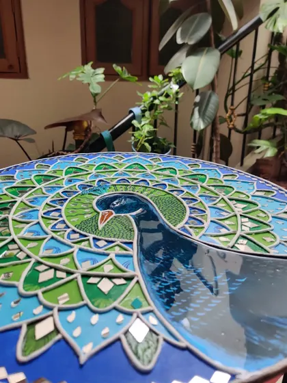 An angled shot of the peacock Lippan art, showing the 3D texture of the clay work.
