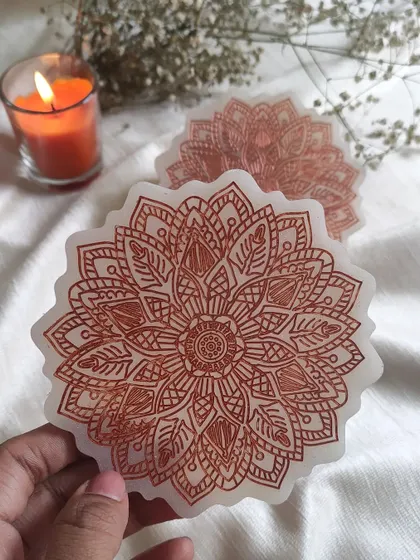 Holding up one of the resin mandala coasters to show the fine lines and beautiful pattern. They are perfect for adding a touch of zen to your coffee break.