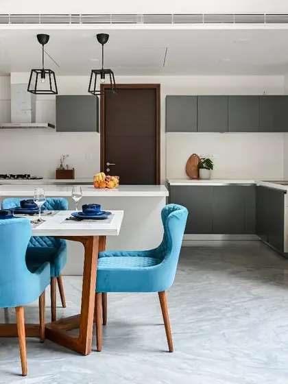 This open-plan layout connects the dining area and kitchen, perfect for modern living. The consistent color palette of grey, white, and blue creates a cohesive and stylish look.