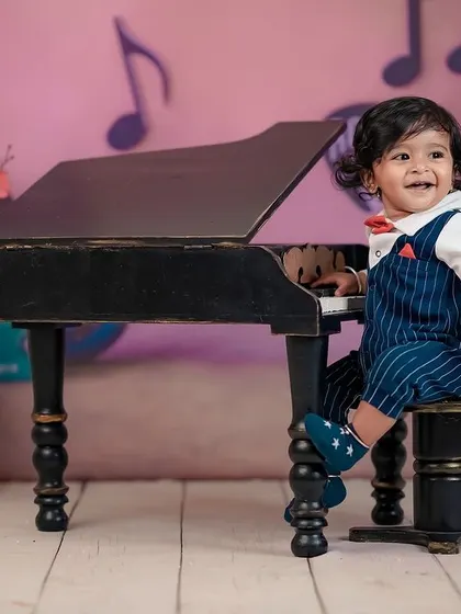 A smiling little pianist enjoying our music-themed studio setup. We love seeing kids interact with our fun props.