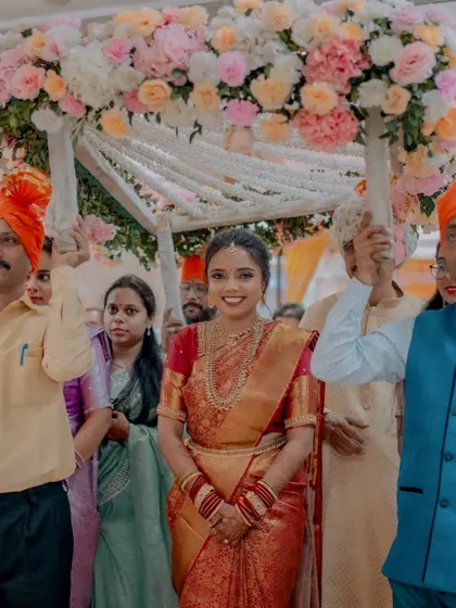 The bride's grand entrance, looking radiant and confident as she walks under the floral canopy.