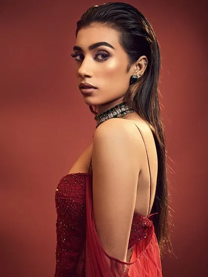 A contemporary editorial look with a wet-hair finish and a bold red outfit. The makeup is minimal yet impactful, focusing on a strong brow and sculpted skin.