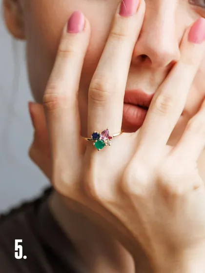 A tight crop on the hands and mouth creates an intimate and intriguing shot. This angle allows the viewer to appreciate the craftsmanship of the clustered gemstone ring up close, making the small details feel significant.